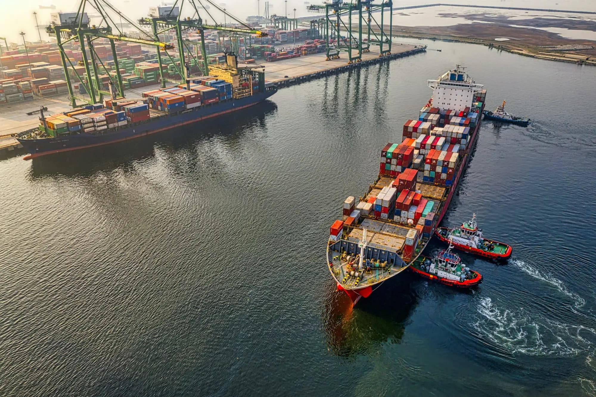 Container ship being guided into port by tugboats